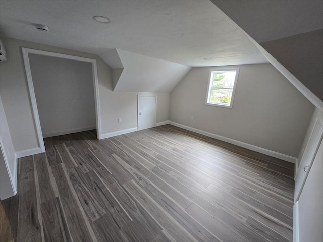 additional living space with baseboards, vaulted ceiling, and dark wood-type flooring