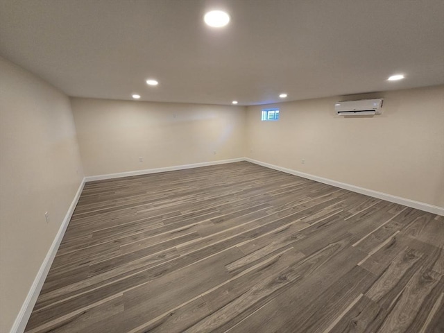 basement with a wall mounted AC, baseboards, dark wood-style floors, and recessed lighting