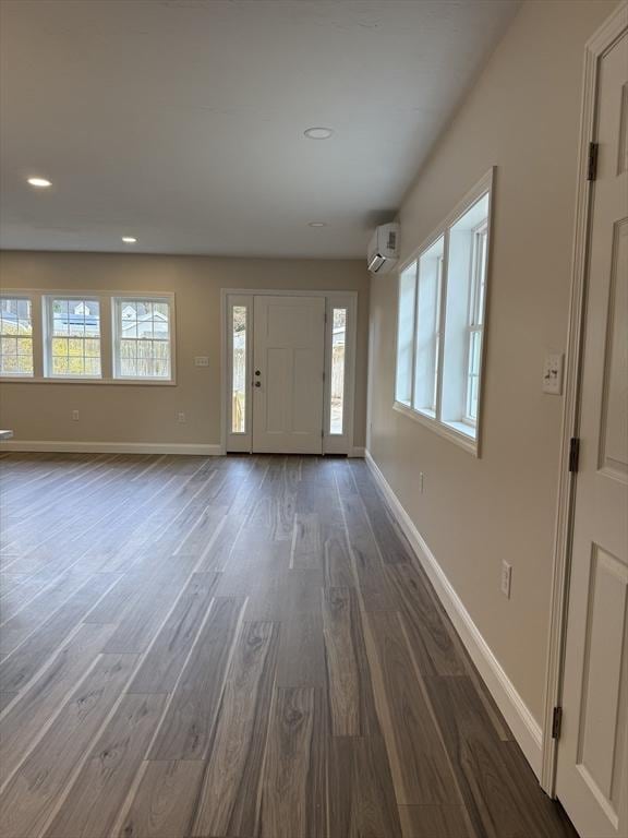 entrance foyer with dark wood finished floors, baseboards, a wall unit AC, and recessed lighting