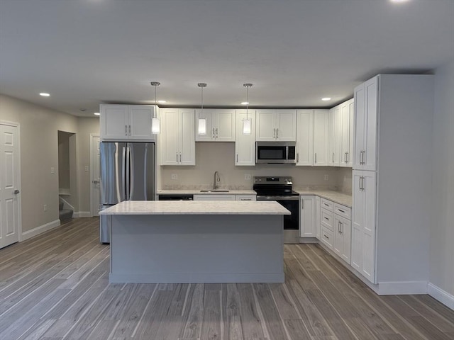 kitchen with baseboards, recessed lighting, appliances with stainless steel finishes, and a center island