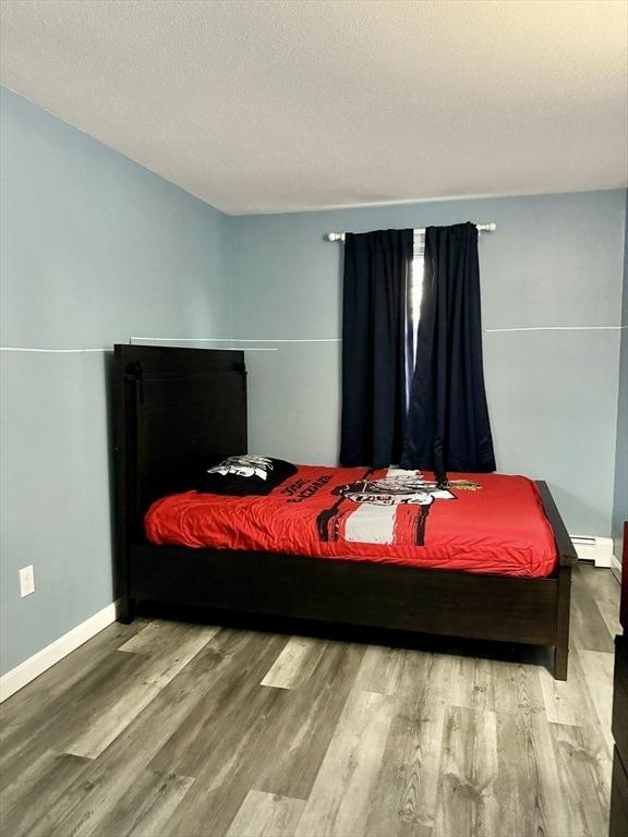 bedroom with hardwood / wood-style flooring and baseboard heating