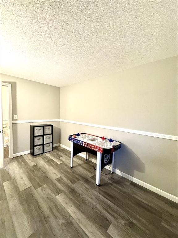 game room featuring wood-type flooring and a textured ceiling