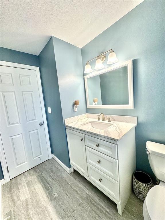 bathroom with vanity, toilet, wood-type flooring, and a textured ceiling