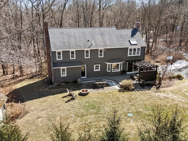 rear view of house featuring a patio, a yard, a fire pit, and a chimney