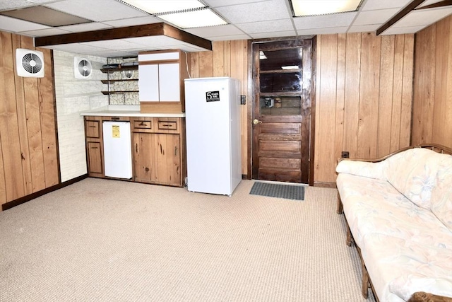 kitchen featuring freestanding refrigerator, wood walls, and a paneled ceiling