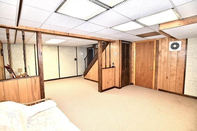 finished below grade area with carpet, wood walls, a paneled ceiling, and stairs