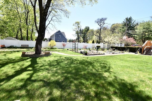 view of yard with a fenced backyard and stairs