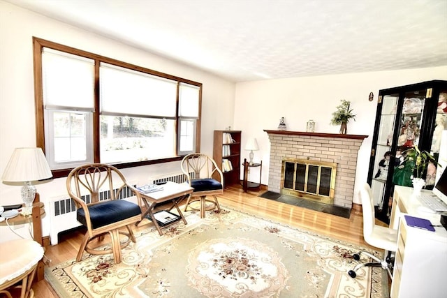 living room with a fireplace, a wealth of natural light, radiator, and wood finished floors