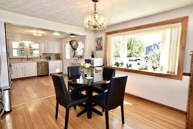 dining space featuring an inviting chandelier, light wood-style flooring, and baseboards