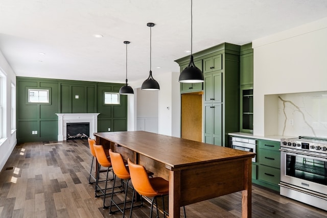 kitchen featuring green cabinetry, decorative light fixtures, dark hardwood / wood-style floors, and stainless steel range oven