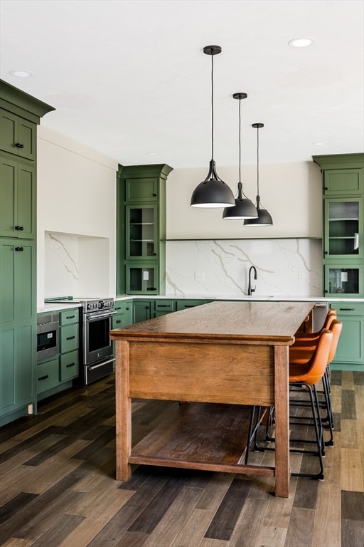 bar with decorative light fixtures, green cabinets, stainless steel appliances, and dark hardwood / wood-style flooring