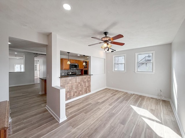 unfurnished living room featuring baseboards, ceiling fan, recessed lighting, and light wood-style flooring