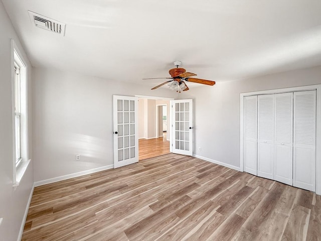unfurnished bedroom featuring visible vents, a closet, baseboards, french doors, and light wood finished floors
