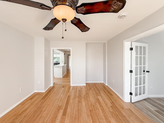 spare room with light wood-style floors, a sink, baseboards, and ceiling fan