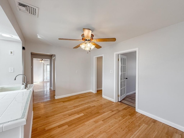 interior space featuring a sink, a ceiling fan, light wood finished floors, and visible vents