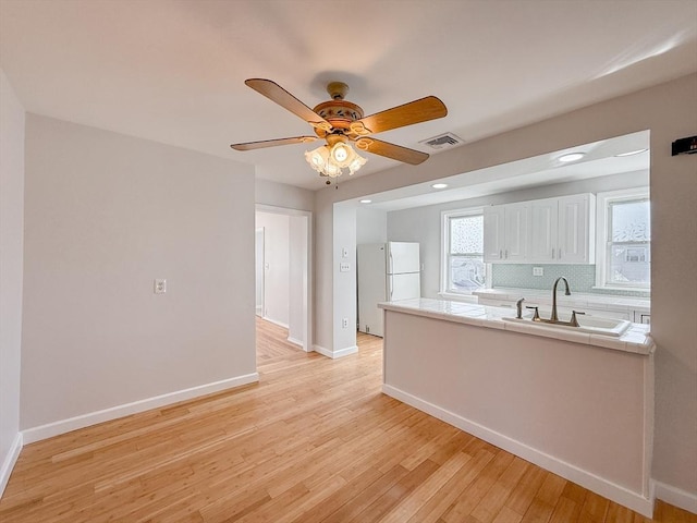 kitchen with visible vents, freestanding refrigerator, tile countertops, white cabinets, and a sink