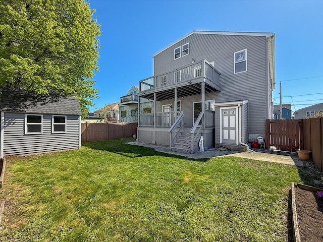 back of property featuring a yard, an outbuilding, a fenced backyard, and a balcony