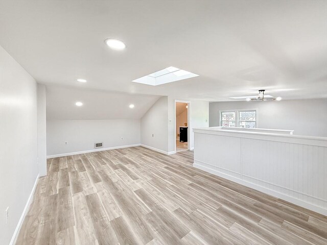 bonus room with ceiling fan, wainscoting, light wood-style flooring, visible vents, and lofted ceiling with skylight