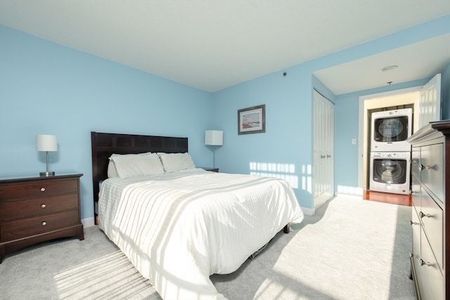 carpeted bedroom with a closet and stacked washer / drying machine