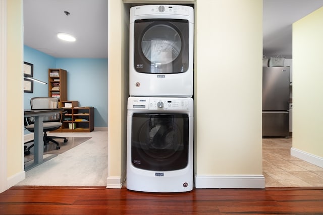 clothes washing area with hardwood / wood-style floors and stacked washer and clothes dryer