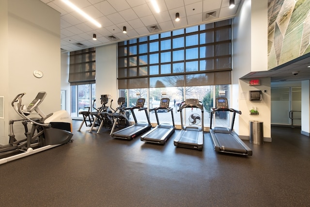 exercise room featuring a drop ceiling and a towering ceiling