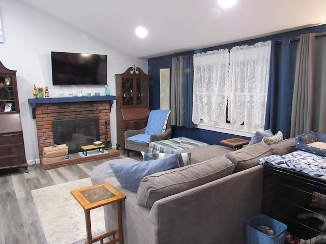 living room with a brick fireplace, lofted ceiling, and light hardwood / wood-style flooring