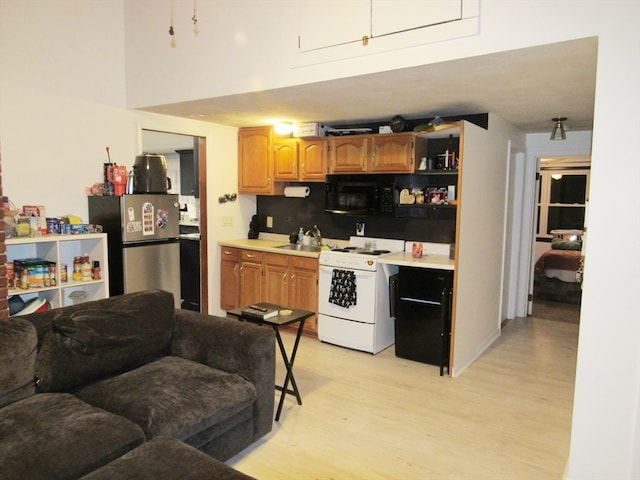 kitchen with decorative backsplash, stainless steel fridge, white range with electric stovetop, sink, and light hardwood / wood-style flooring