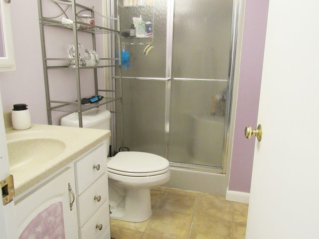 bathroom featuring toilet, a shower with door, vanity, and tile patterned flooring