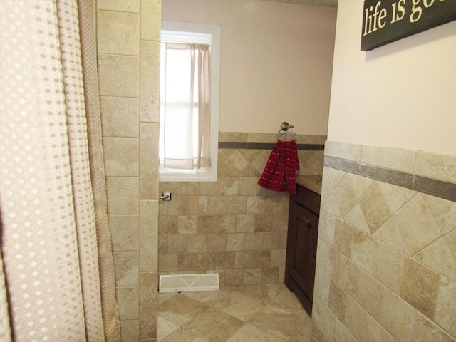 bathroom featuring vanity and tile walls