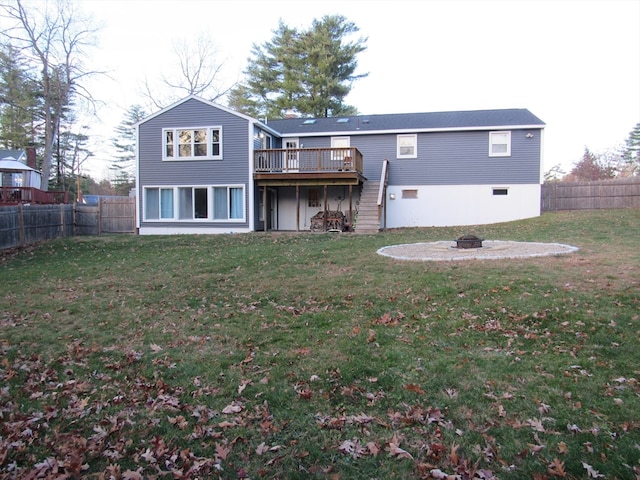 back of property with a deck, an outdoor fire pit, and a lawn