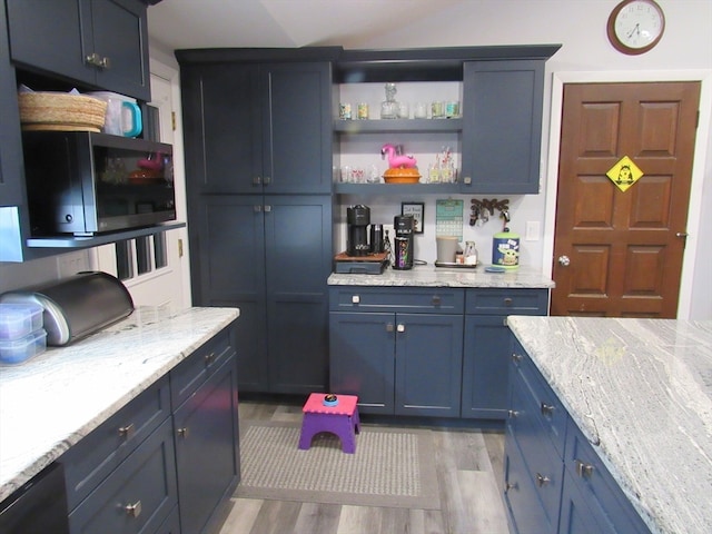 kitchen with blue cabinetry, light hardwood / wood-style floors, and light stone countertops