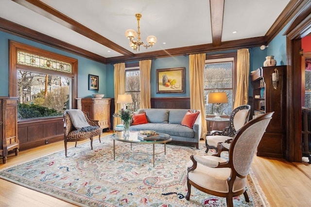 living area featuring ornamental molding, a notable chandelier, beam ceiling, and light hardwood / wood-style flooring