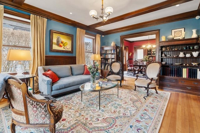 living area with a notable chandelier, ornamental molding, and light hardwood / wood-style floors