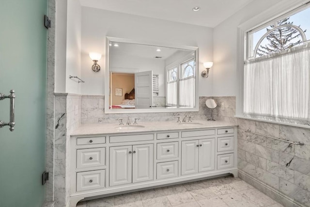 bathroom featuring vanity, a shower with shower door, tile walls, and a wealth of natural light