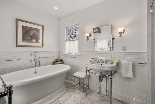 bathroom featuring a tub, sink, and tile walls