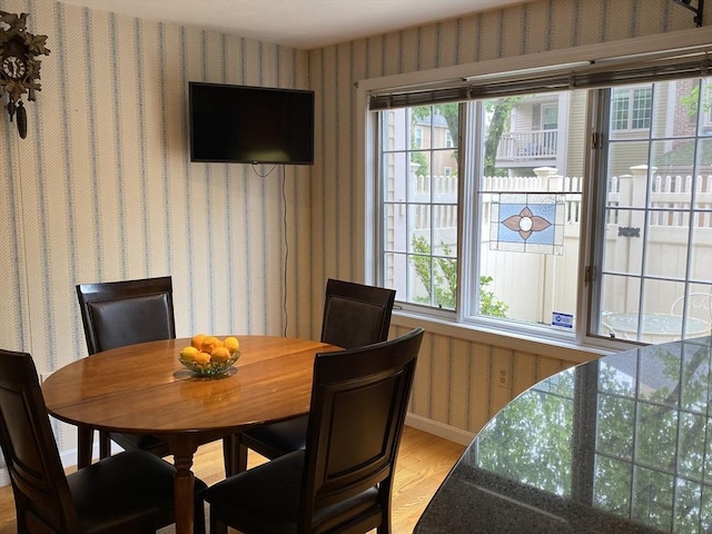 dining space featuring wallpapered walls, light wood-style floors, and baseboards