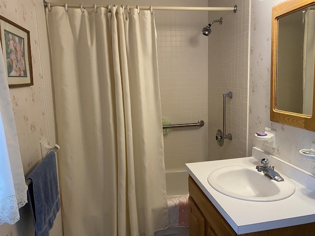 bathroom with vanity, shower / bath combo with shower curtain, and wallpapered walls
