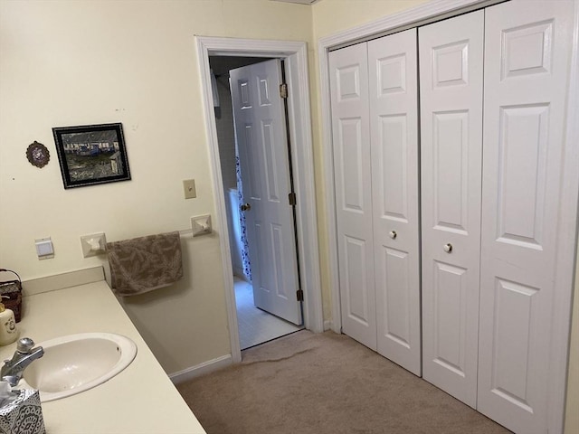 bathroom with a sink, a closet, and baseboards