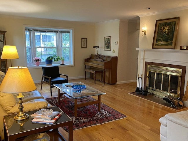 living area featuring crown molding, wood finished floors, a fireplace, and baseboards