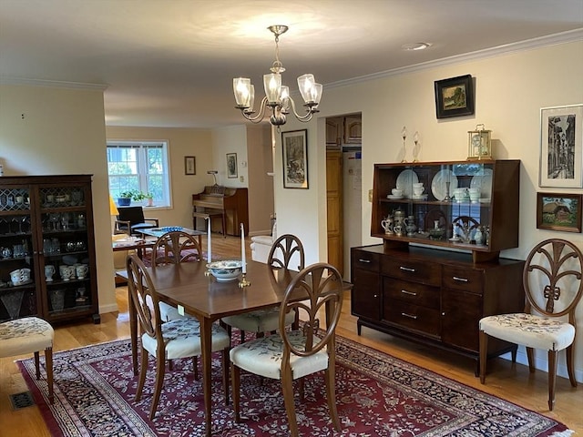 dining room with light wood finished floors, a chandelier, and ornamental molding