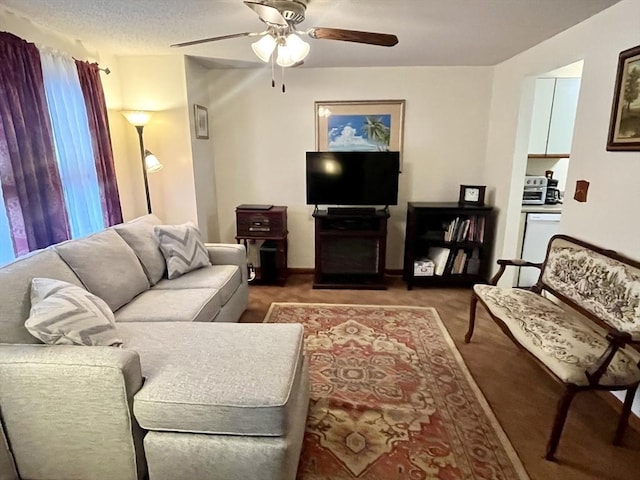 carpeted living room featuring ceiling fan and a textured ceiling