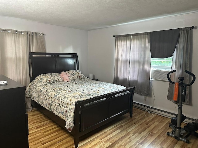 26 Burnap Rd Unit 6, Holliston, MA 01746 - bedroom featuring light wood-style flooring, cooling unit, a textured ceiling, and baseboard heating