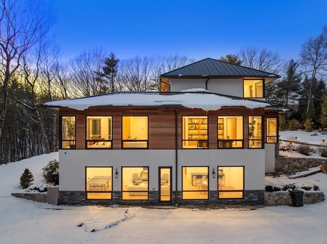 snow covered back of property featuring a balcony