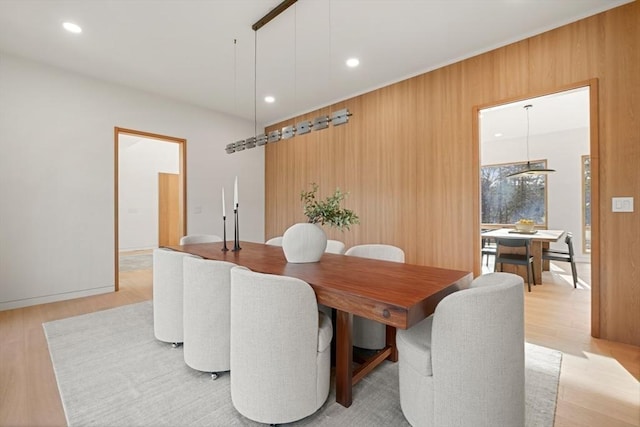 dining room with wooden walls and light hardwood / wood-style floors