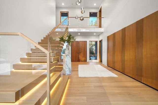 entrance foyer with a towering ceiling and light hardwood / wood-style floors