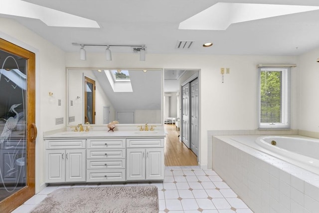 376 Flint St, Barnstable, MA 02648 - bathroom featuring a skylight, double vanity, a garden tub, track lighting, and recessed lighting