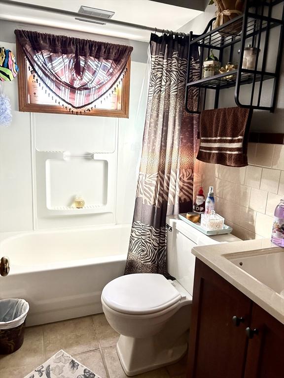 full bath featuring shower / bath combination with curtain, backsplash, toilet, vanity, and tile patterned flooring