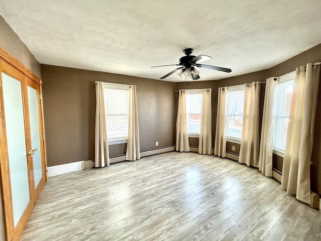 empty room with a healthy amount of sunlight, light wood-style floors, ceiling fan, and baseboards