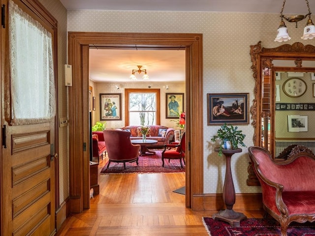 interior space featuring light wood finished floors, wallpapered walls, and a chandelier