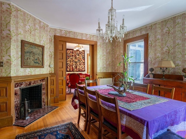 dining area featuring a chandelier, wallpapered walls, wainscoting, hardwood / wood-style floors, and a fireplace